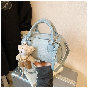 Close-up of light blue bowling bag with lychee grain texture and cute teddy bear charm