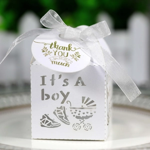 Detail of white laser-cut 'It's A Boy' favor box with satin ribbon and thank you tag
