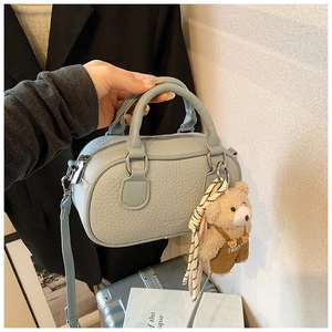 Close-up of light blue bowling bag in lychee leather with cute plush bear charm