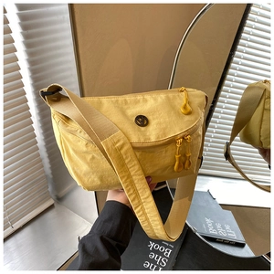 Detail of yellow nylon crossbody bag with metal logo and adjustable wide strap