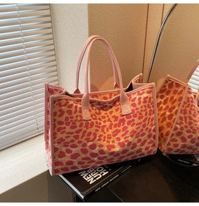 Close-up of pink and orange leopard print canvas tote bag with woven strap in natural light