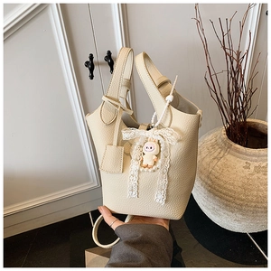 Detail of off-white lychee pattern bucket bag with cute bunny pendant and leather tag