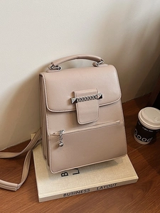 Elegante beige Kunstleder-Handtasche mit Silberkette und Nieten auf einem Schreibtisch