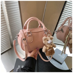 Pink pebbled leather boston bag featuring a cute teddy bear charm and adjustable strap