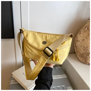 Macro shot of warm yellow nylon crossbody bag with textured fabric and metallic logo detail
