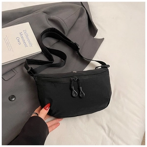 Close-up of minimalist black crossbody bag with dual zippers and adjustable nylon strap