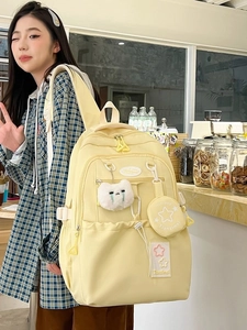 Minimalist light yellow waterproof backpack with cute plush pendants and multi-pockets