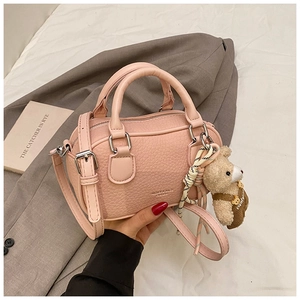 Detail of light pink pebble leather bowling bag with cute teddy bear plush charm