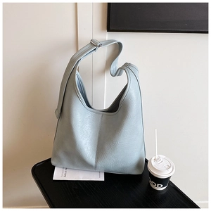 Detail of light blue bucket bag with pebble leather texture and vertical stitching