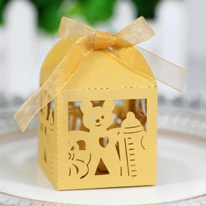 Detail of yellow laser-cut bear candy box with a golden organza bow for baby shower