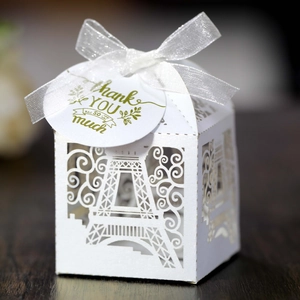 Close-up of white laser-cut favor box with Eiffel Tower pattern and thank you tag