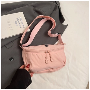 Detail of pink nylon crescent bag featuring double zippers and adjustable wide shoulder strap