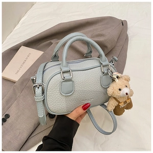 Detailed view of blue bowling bag with pebble leather and cute bear charm accessory