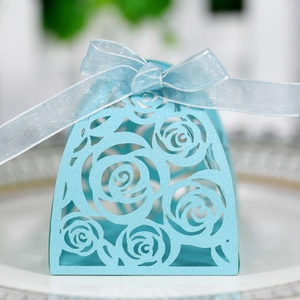 Close-up of light blue laser-cut wedding candy box with rose patterns and ribbon bow