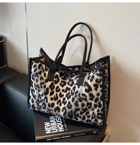 Close-up of leopard print tote bag with black strap resting on books in indoor setting