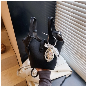 Detail of black pebbled leather bucket bag with decorative pearl lace and cartoon charms