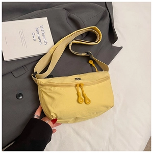 Detail of light yellow nylon crescent bag with dual round zipper pulls on grey blazer