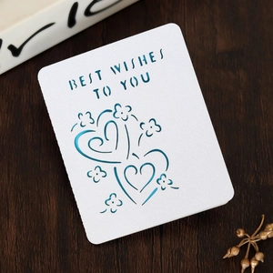 Laser-cut white greeting card with Heart patterns and Best Wishes text on wooden background