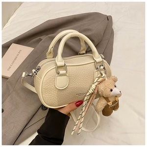 Detail of cream bowling bag with lychee texture and cute plush bear charm on side