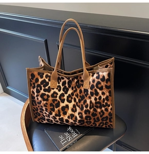 Close-up of leopard print tote bag with thick fabric handles on a leather chair