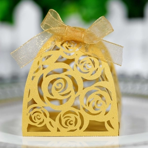 Macro view of gold laser-cut rose hollow candy box with matching organza ribbon bow