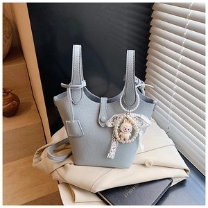 Detail of light blue bucket bag with pebble leather texture and pearl lace bunny charm