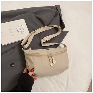 Close-up of beige nylon crescent bag with adjustable strap and designer zip on suit jacket
