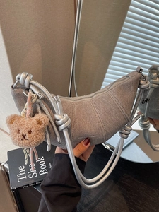 Graue Croissant-Tasche mit Silbergriff und Plüschbär-Anhänger für modernen Schick