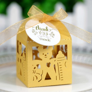 Détail de boîte cadeau jaune découpée au laser avec motif ours, ruban et étiquette merci