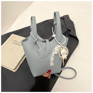 Close-up of light blue bucket bag with lychee texture and pearl lace charm