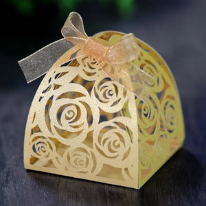 Macro detail of laser-cut rose pattern on golden pearlescent paper gift box with ribbon