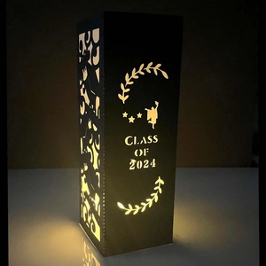 Close-up of Class of 2024 laser-cut paper lantern with warm glowing silhouette effect