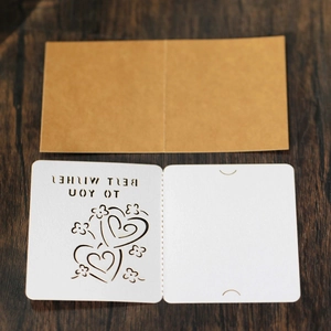Detail of laser-cut wedding card with hollow heart pattern and kraft envelope
