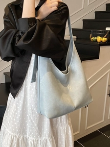Minimalist light blue hobo bucket bag with a soft wrinkled texture and wide shoulder strap