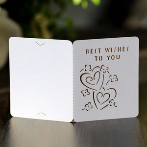 Detail of laser-cut white greeting card with Heart and Best Wishes text on wood