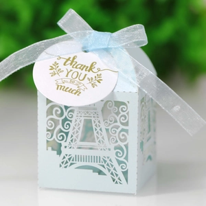 Close-up of laser-cut Eiffel Tower wedding favor box in light blue with white ribbon