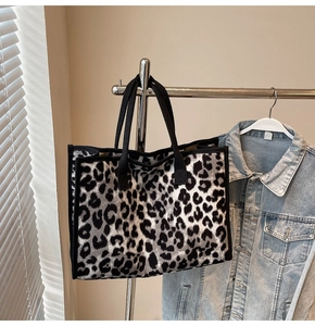 Detailed close-up of a large leopard print tote bag hanging on a metal rack