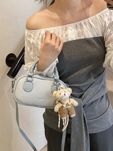Light blue bowling style crossbody bag with leather texture and cute bear charm