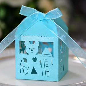 Detailed laser-cut blue baby shower favor box with bear and ribbon on a plate