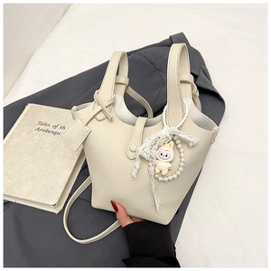 Detail view of cream bucket bag with lychee texture and cute rabbit charm