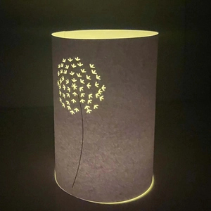Detail of laser-cut dandelion pattern on white night light with warm LED glow