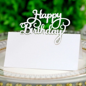 Detail of white laser-cut 'Happy Birthday' place card on a gold-rimmed decorative plate