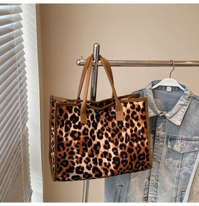 Detail of a large leopard print canvas tote bag featuring brown woven straps and vintage texture