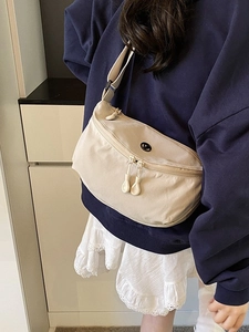 Minimalist beige nylon crossbody crescent bag with circular logo and dual zip hardware