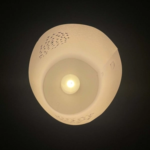 Top view of hollow white paper lampshade with bird silhouettes and warm LED light effect