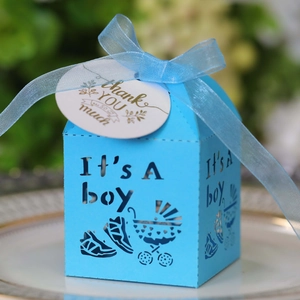 Detail of light blue laser-cut baby shower candy box with It's A Boy cutout and ribbon