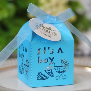 Detail of blue 'It's A Boy' favor box with laser-cut stroller and ribbon decoration