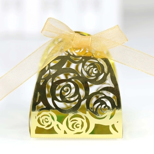 Close-up of champagne gold laser-cut candy box with rose pattern and organza bow
