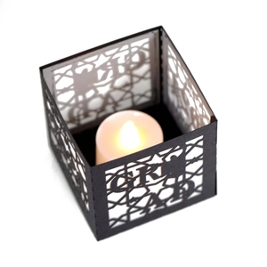 Macro shot of a black graduation lantern with hollow GR AD text and a soft glowing candle