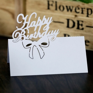 Macro shot of white laser-cut Happy Birthday place card with hollow bow-knot detail